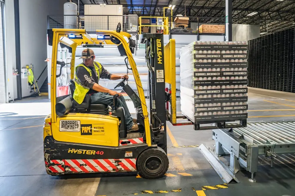 A man driving a yellow forklift in a warehouse.